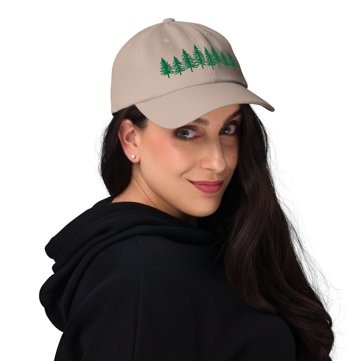 Female model wearing the stone Into the Pines baseball hat by Klemm & Co., angled right to show the embroidered pine tree design in green thread.