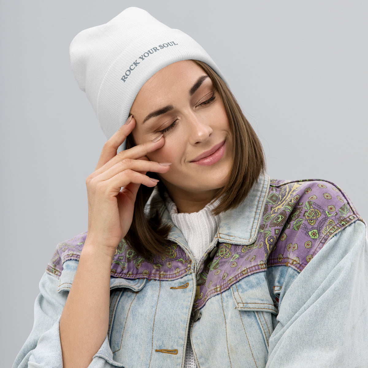 Female model wearing the white Rock Your Soul toque by Klemm & Co., front-right view showing ROCK YOUR SOUL embroidered in grey thread.