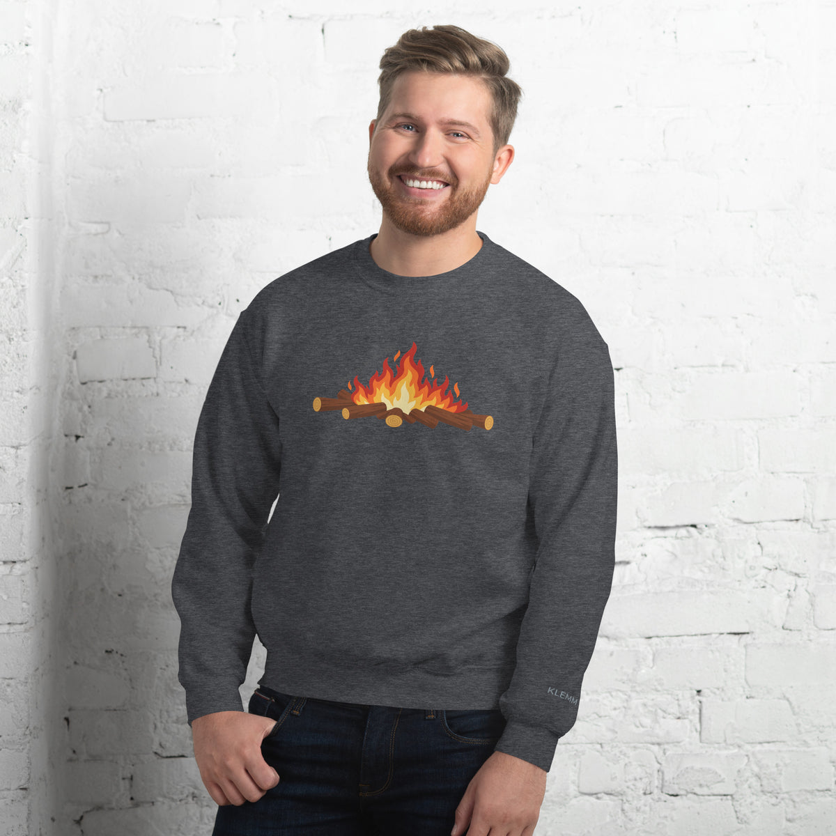 Male model wearing the dark heather grey Meet Me by the Fire crewneck sweatshirt by Klemm & Co., front view showing the printed campfire design.