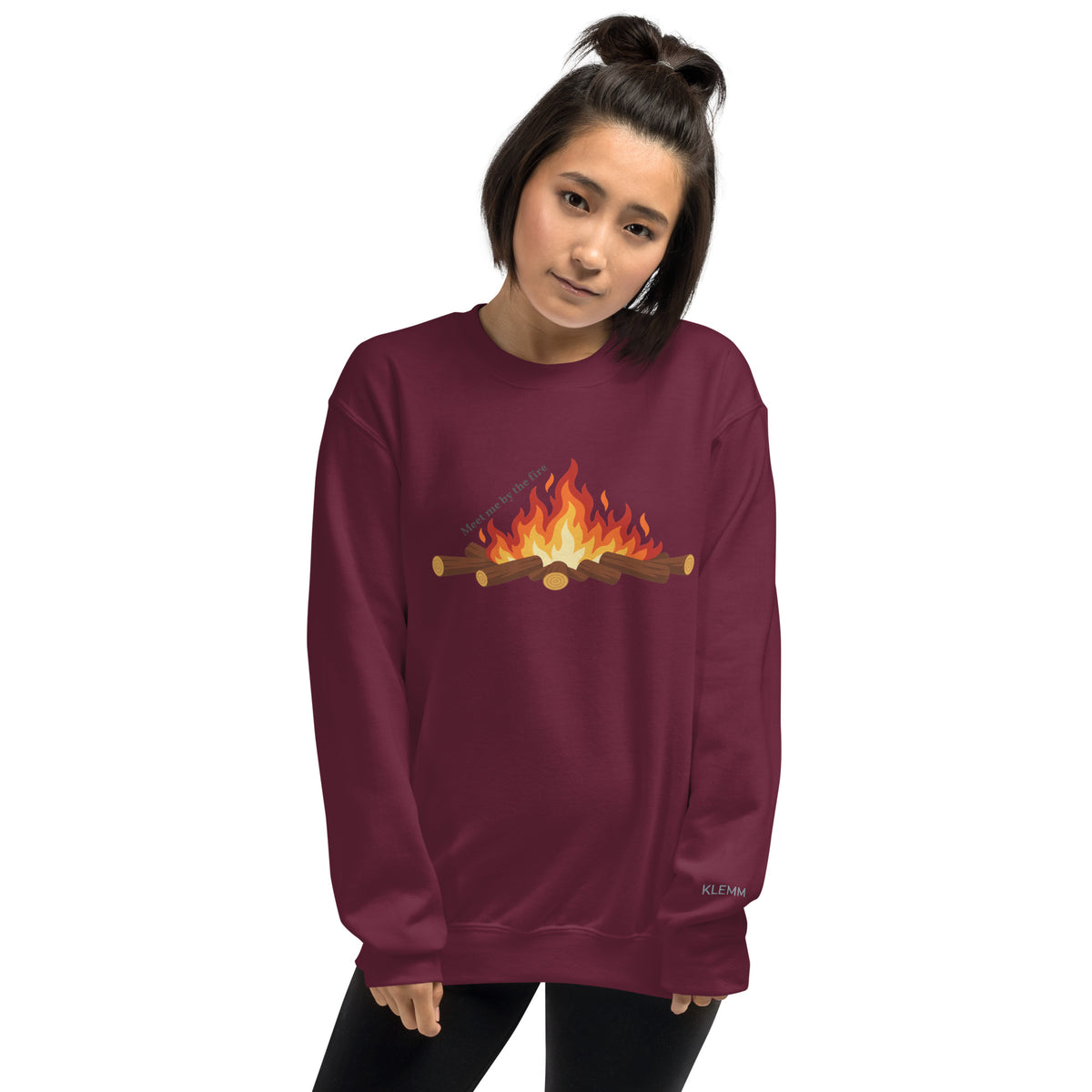 Female model wearing the maroon Meet Me by the Fire crewneck sweatshirt by Klemm & Co., front view showing the printed campfire design.