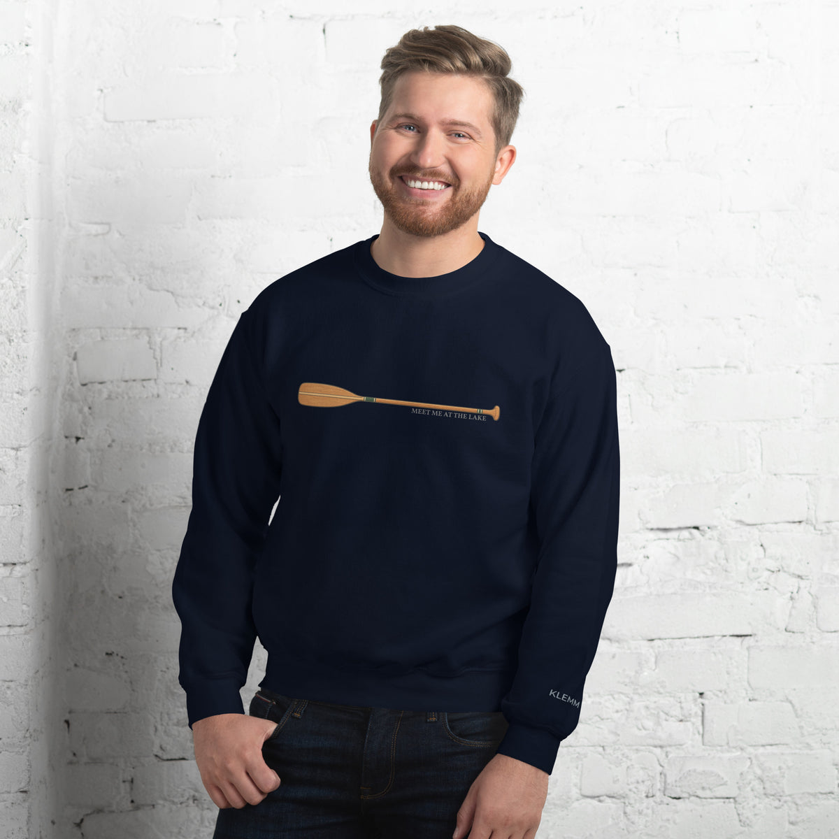 Male model wearing the navy Meet Me at the Lake crewneck sweatshirt by Klemm & Co., front view showing the printed paddle design.