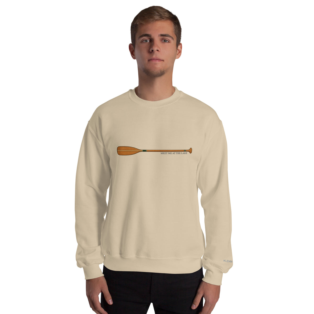 Male model wearing the sand Meet Me at the Lake crewneck sweatshirt by Klemm & Co., front view showing the printed paddle design.