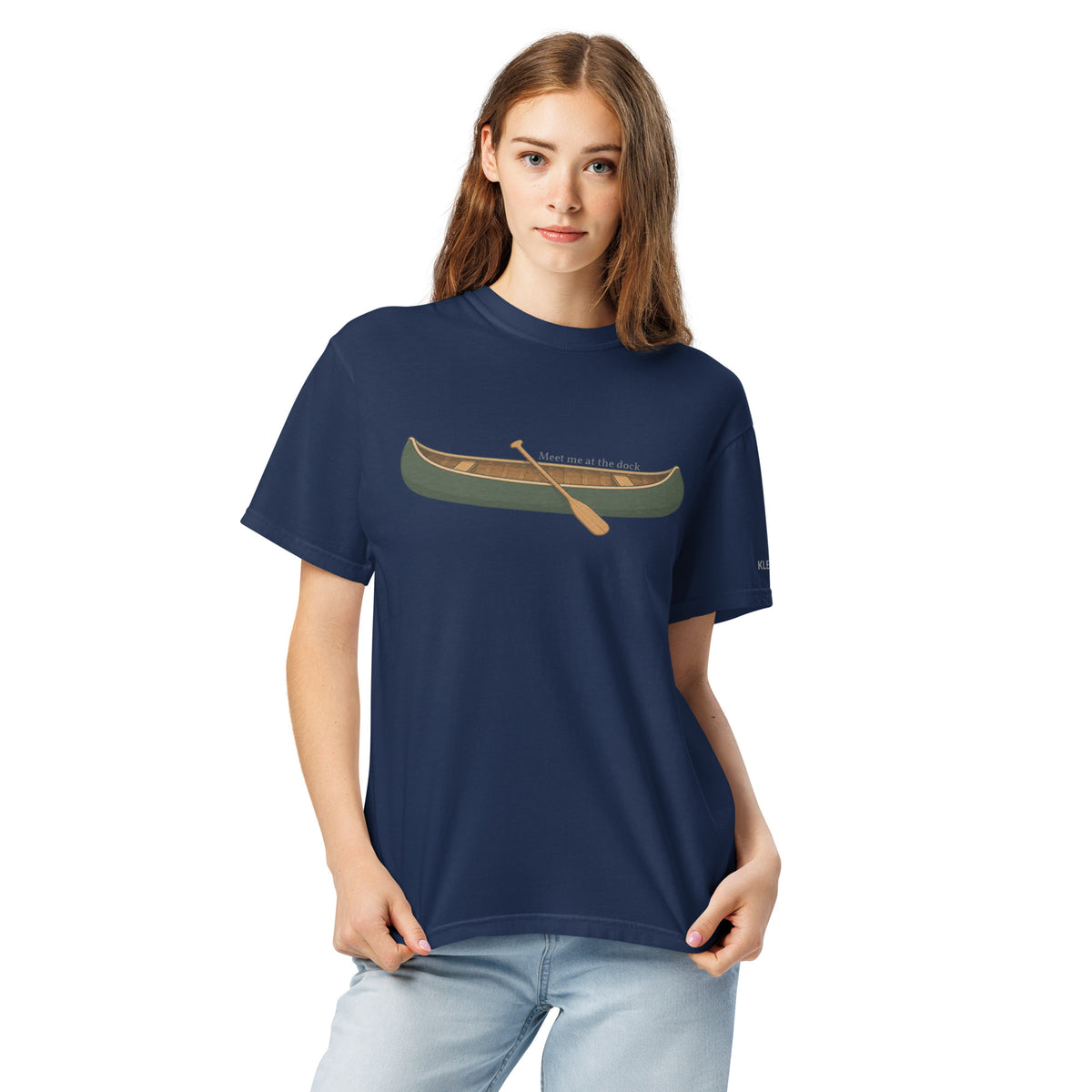 Female model wearing the navy Meet Me at the Dock graphic T-shirt by Klemm & Co., front view showing the printed canoe design.