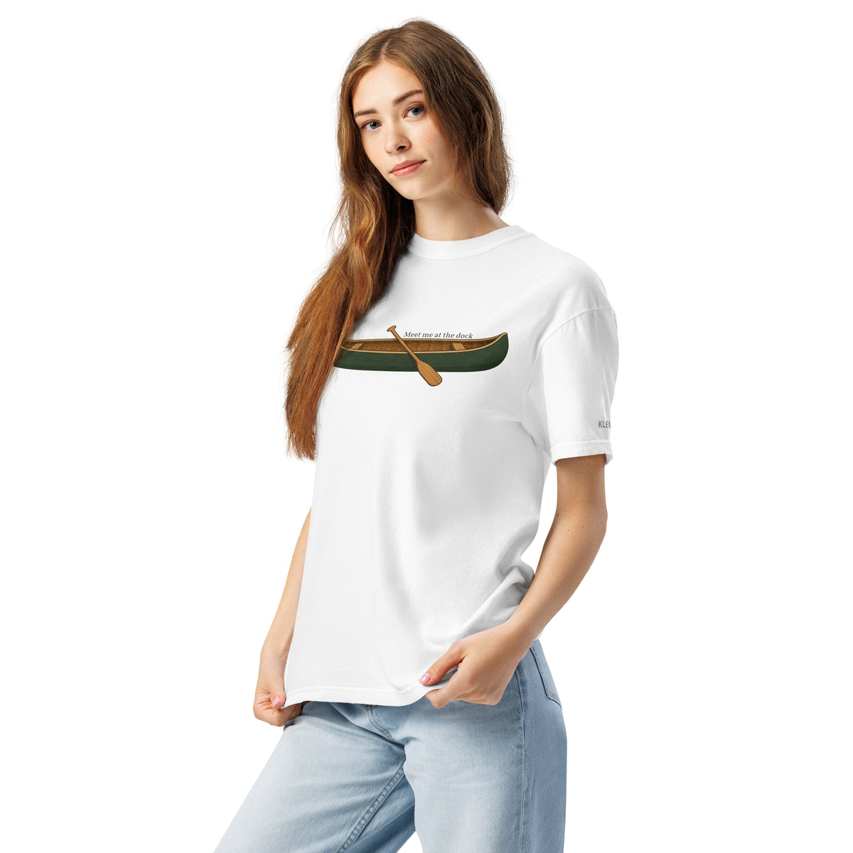 Female model wearing the white Meet Me at the Dock graphic T-shirt by Klemm & Co., front-left view showing the printed canoe design and KLEMM sleeve branding.