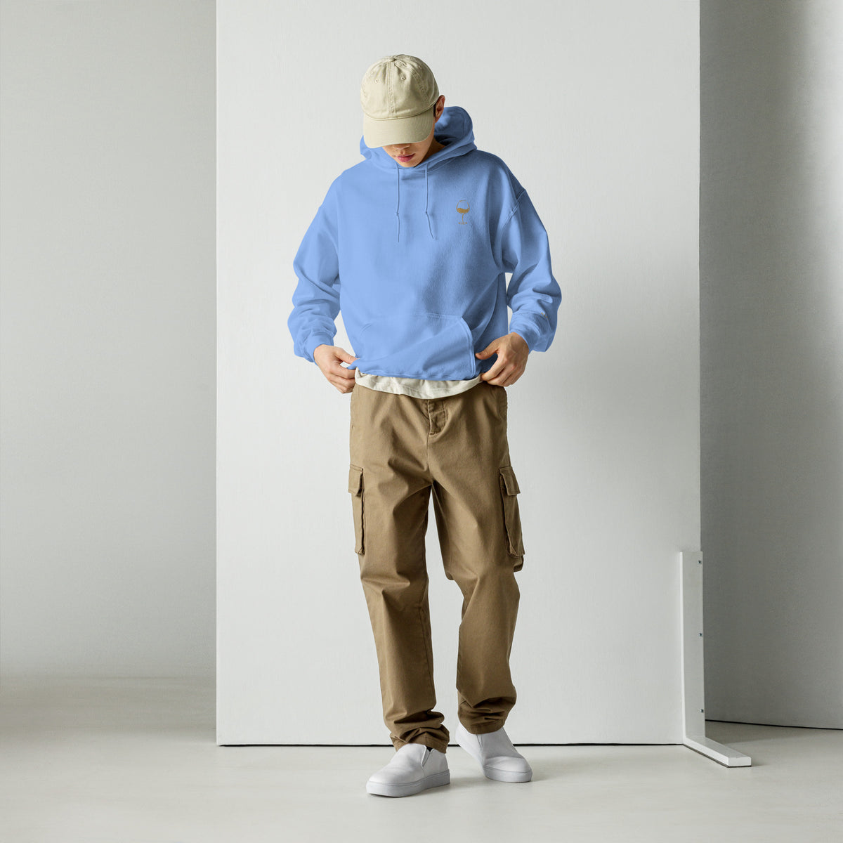 Male model wearing the Carolina blue Poured for This wine hoodie by Klemm & Co., full-body front view showing the gold embroidered wine glass design.