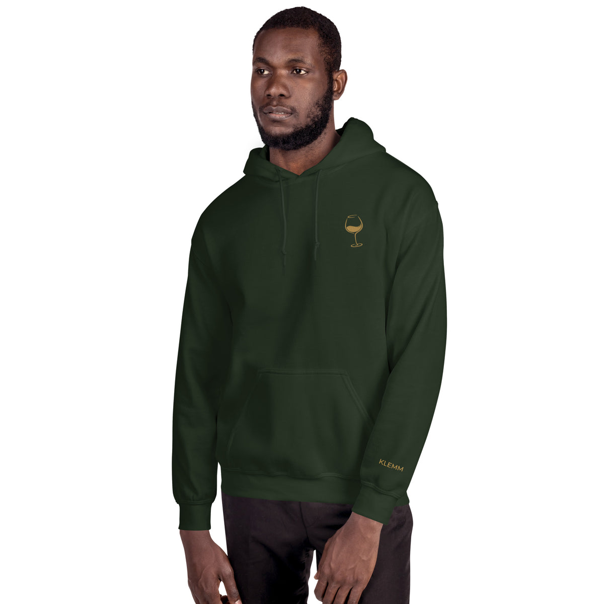 Male model wearing the forest green Poured for This wine hoodie by Klemm & Co., front-left view showing the gold embroidered wine glass and KLEMM sleeve branding.