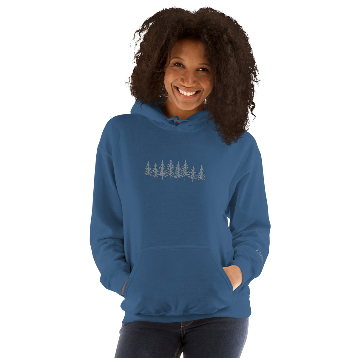 Female model wearing the indigo blue Into the Pines embroidered hoodie by Klemm & Co., front view showing the pine tree design embroidered in grey thread.