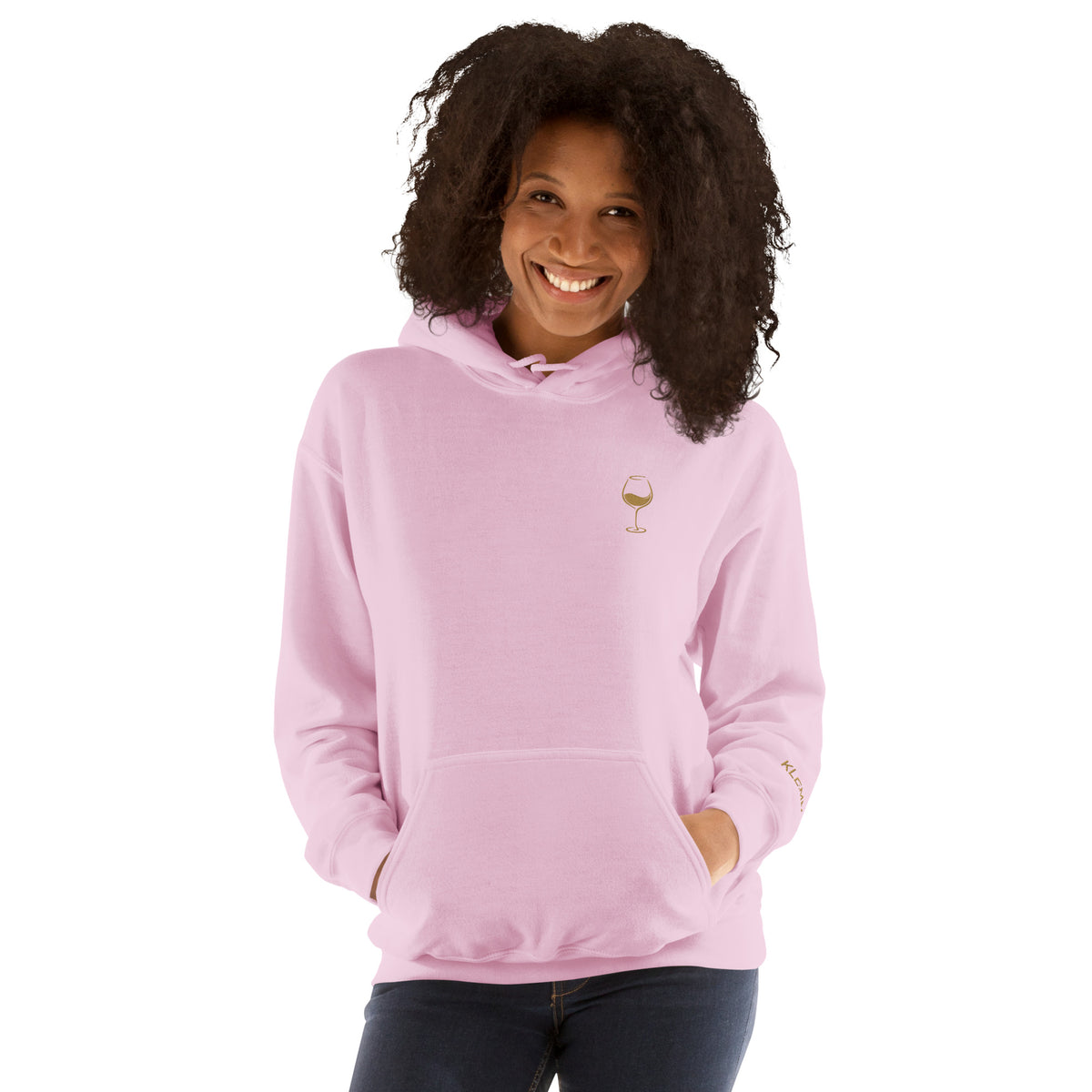 Female model wearing the light pink Poured for This wine hoodie by Klemm & Co., front view showing the gold embroidered wine glass design.