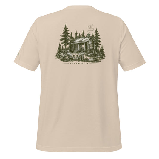 Soft cream Meet Me at the Cabin graphic T-shirt by Klemm & Co., back view with a woodland cabin and pine tree design.